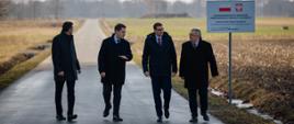 Premier, minister infrastruktury oraz poseł Daniel Milewski idą na tle drogi.