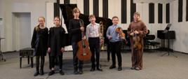 Wszyscy wykonawcy stoją na scenie ze swoimi instrumentami.