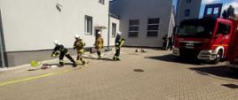 Strażacy rozwijający węże pożarnicze podczas ćwiczeń