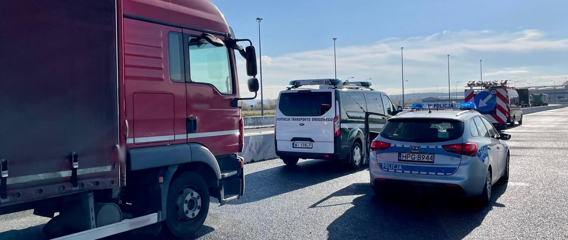 Od lewej: przód i prawy bok kabiny ciężarówki zatrzymanej do kontroli drogowej na małopolskim odcinku autostrady A4. Obok stoi oznakowany furgon Inspekcji Transportu Drogowego i radiowóz Policji.