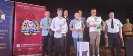 Na zdjęciu widzimy finalistów w II kategorii wiekowej. W tle znajdują się osoby wręczające nagrody i dyplomy, w tym Rektor Uczelni, za-ca Podkarpackiego Komendanta Wojewódzkiego PSP, V-ce Starosta Sanocki oraz przedstawiciel ZOSP RP w Rzeszowie.