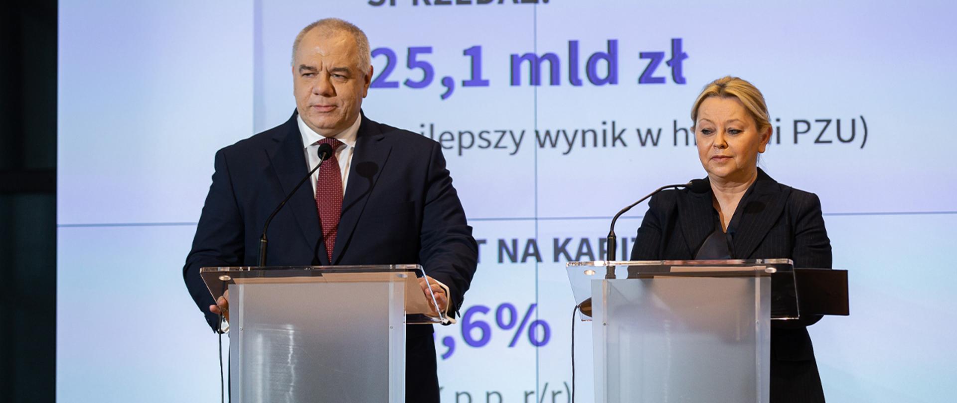 Przy mównicach stoją wicepremier Jacek Sasin i prezes Zarządu Grupy PZU Beata Kozłowska-Chyła. W tle ścianka z wynikami. 