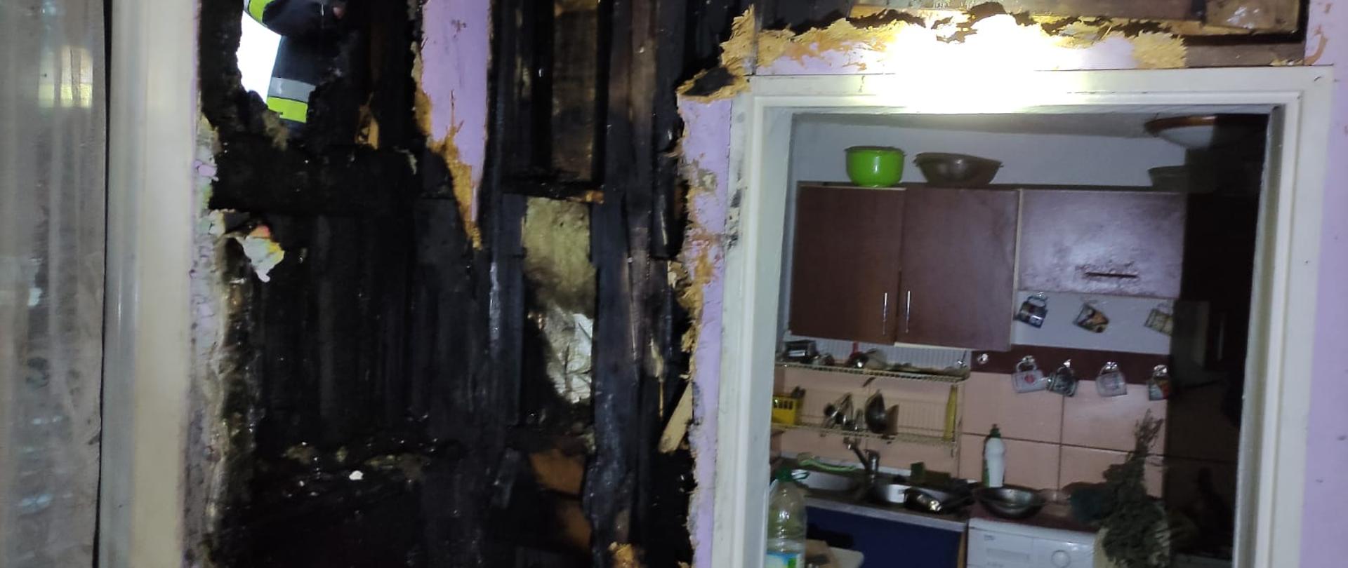 Na zdjęciu widoczny jest wnętrze budynku ze spaloną ścianą przy kominku