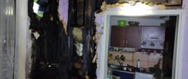 Na zdjęciu widoczny jest wnętrze budynku ze spaloną ścianą przy kominku.