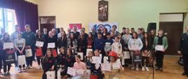 uczniowie biorący udział w eliminacjach powiatowych Ogólnopolskiego Turnieju Wiedzy Pożarniczej “Młodzież Zapobiega Pożarom” w Kozienicach zdjęcie grupowe wraz z komisją sędziowską i zaproszonymi gośćmi 