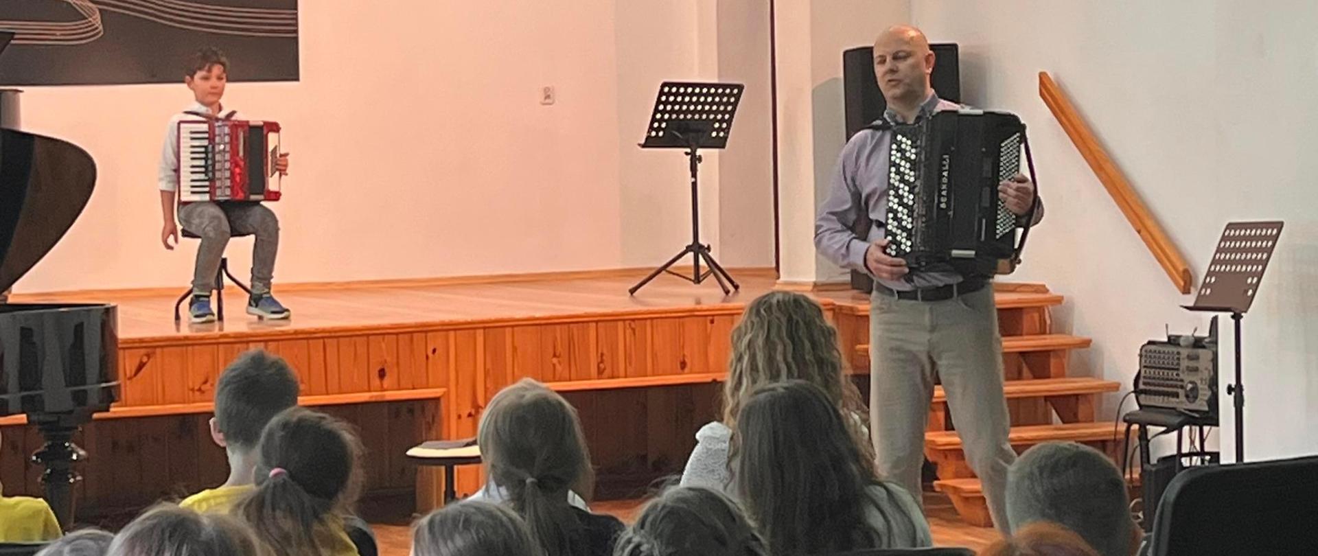 Zdjęcie przestawiające wykonawców koncertu w ramach zorganizowanego dla szkół poranka muzycznego. Koncert odbył się 16 maja 2024 r. w auli szkoły.