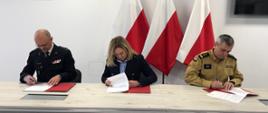 Przedstawiciele Państwowej Straży Pożarnej oraz starosta powiatu kościerskiego podpisują dokumenty.