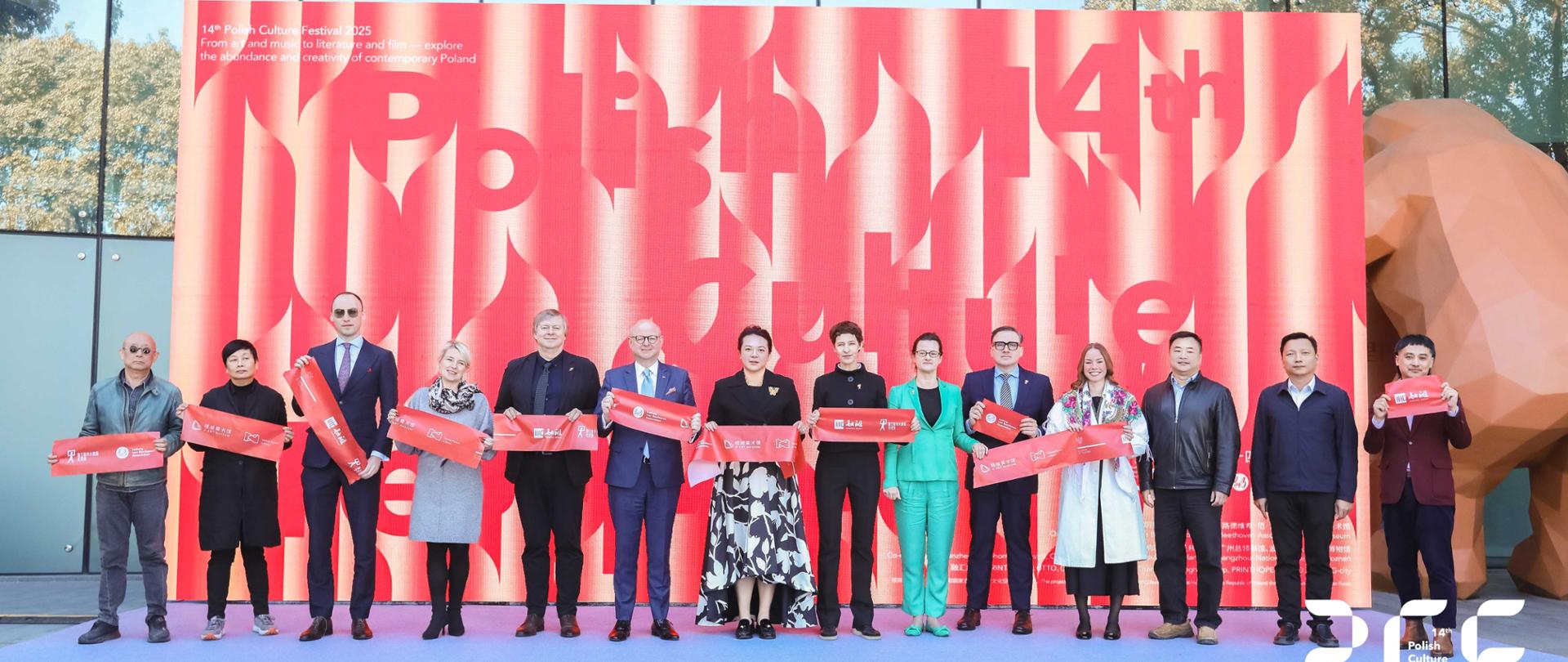 Grupowe zdjęcie uczestników wernisażu wystawy Andrzeja Klimowskiego przed wejściem do G Art Museum w Fuzhou, na tle czerwonego baneru wystawy.