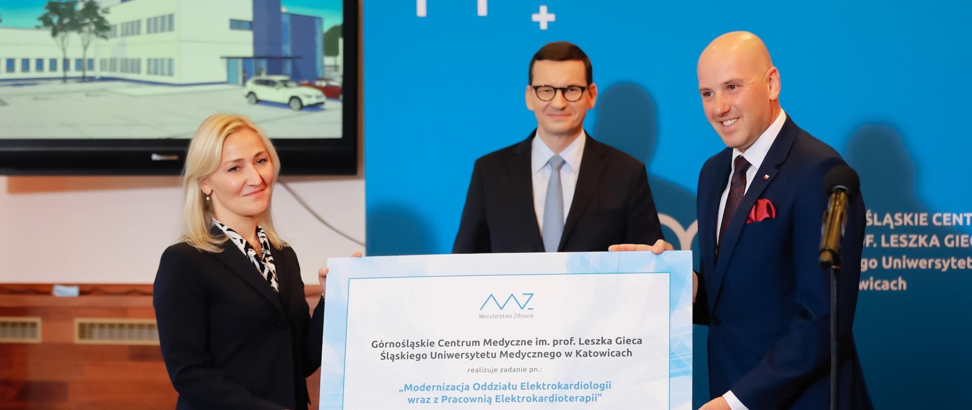 Premier Mateusz Morawiecki przekazuje symboliczny czek.