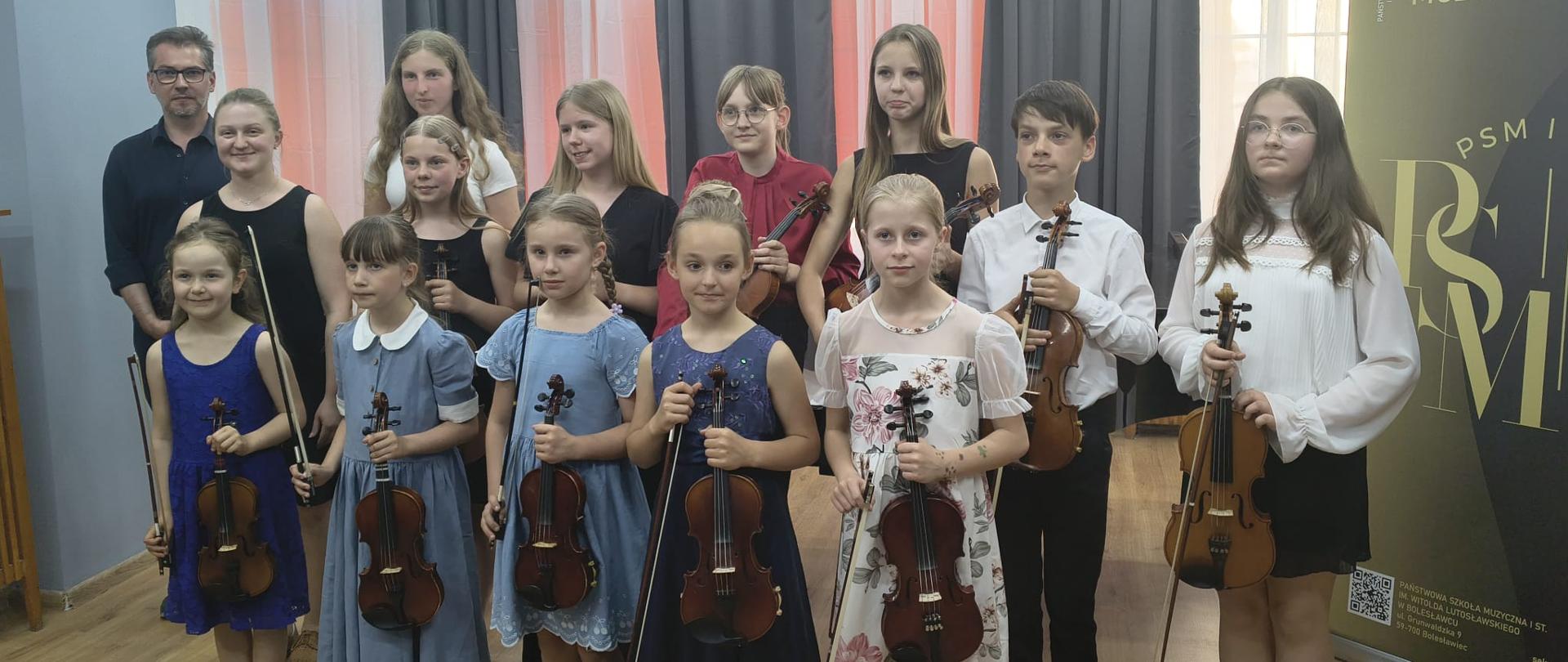Zdjęcie przedstawiające wykonawców popisu klasy skrzypiec pani Kingi Biesiadeckiej, który odbył się 26 maja 2026 roku w małej auli, sali nr 3 w tzw. "starym" budynku szkoły.