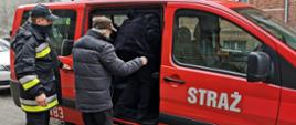 Strażak w maseczce ochronnej pomagający dwóm osobom wejść do samochodu