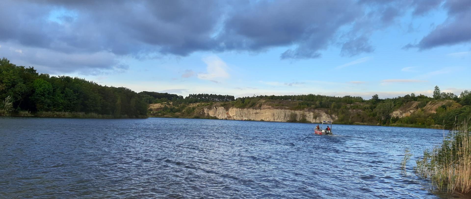 Strażacy prowadzą działania ratownicze na terenie zbiornika wodnego z wykorzystaniem łodzi