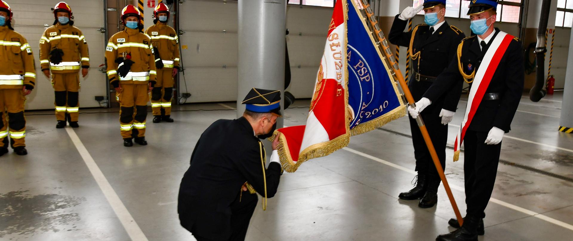 Komendant PSP klęka i całuje sztandar