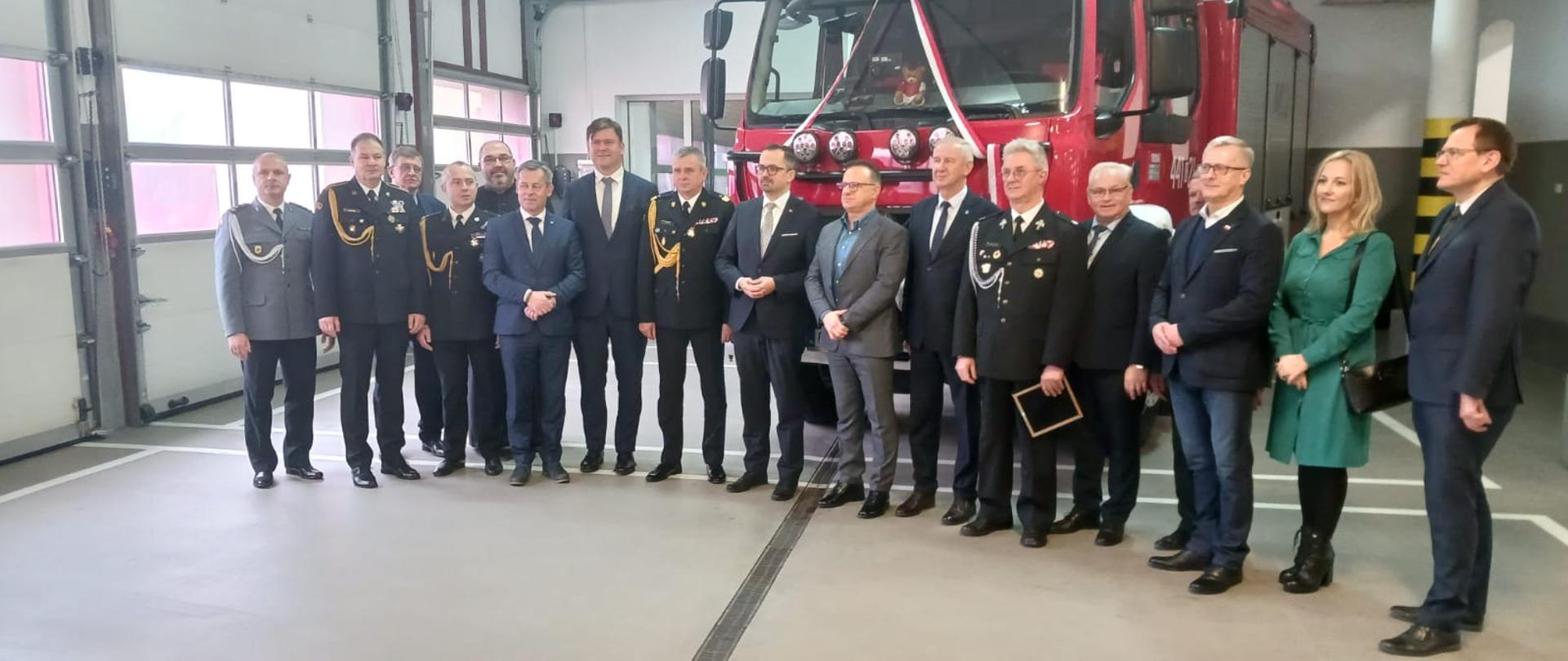 Pamiątkowe zdjęcie uczestników uroczystości na tle nowego samochodu.