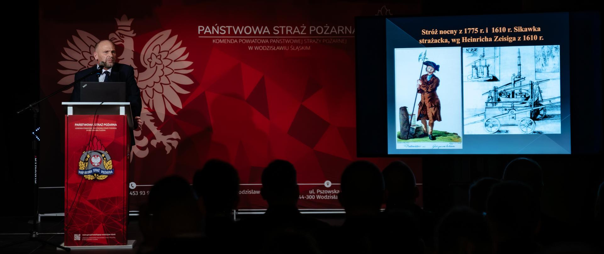 Dyrektor muzeum przedstawia na prezentacji multimedialnej historię pożarnictwa na ziemi wodzisławskiej