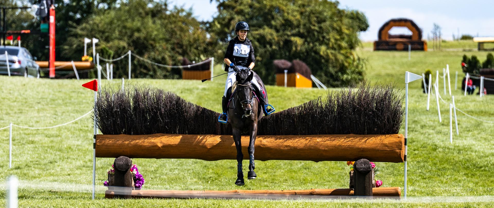 Dżokejka na koniu podczas przeskakiwania przeszkody