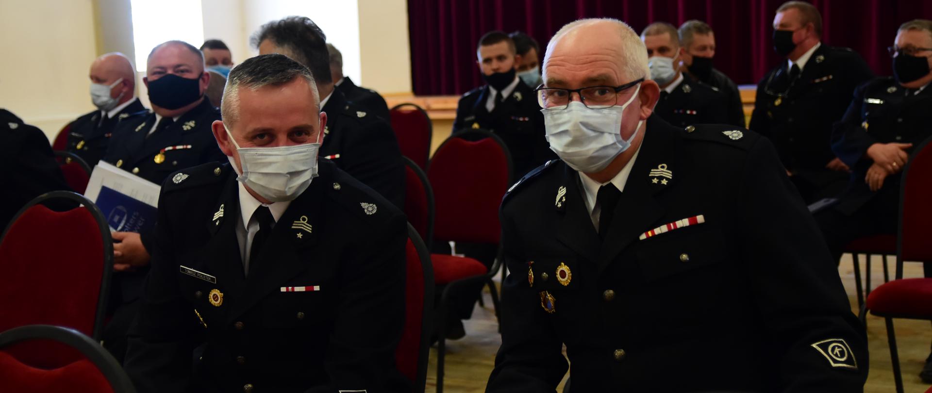 Na zdjęciu druhowie OSP w mundurach wyjściowych. W pozycji siedzącej przysłuchują się dyskusji o projekcie ustawy o ochotniczej straży pożarnej. W tle wystrój sali widowiskowej OSP w Bysławiu.