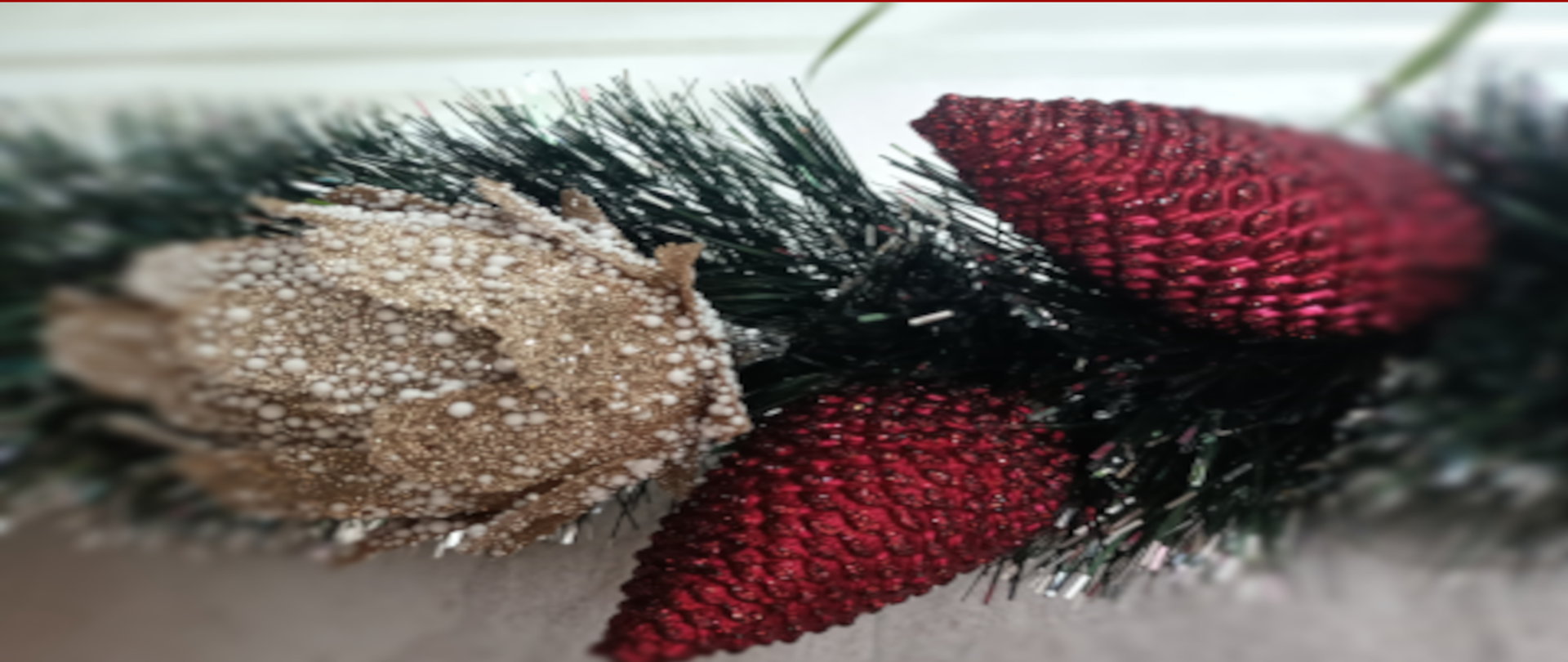 Trzy bombki na gałązce, dwie czerwone szyszki i złota róża.