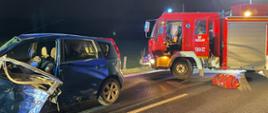 Widać uszkodzony samochód od strony kierowcy, po prawej, samochód strażacki
