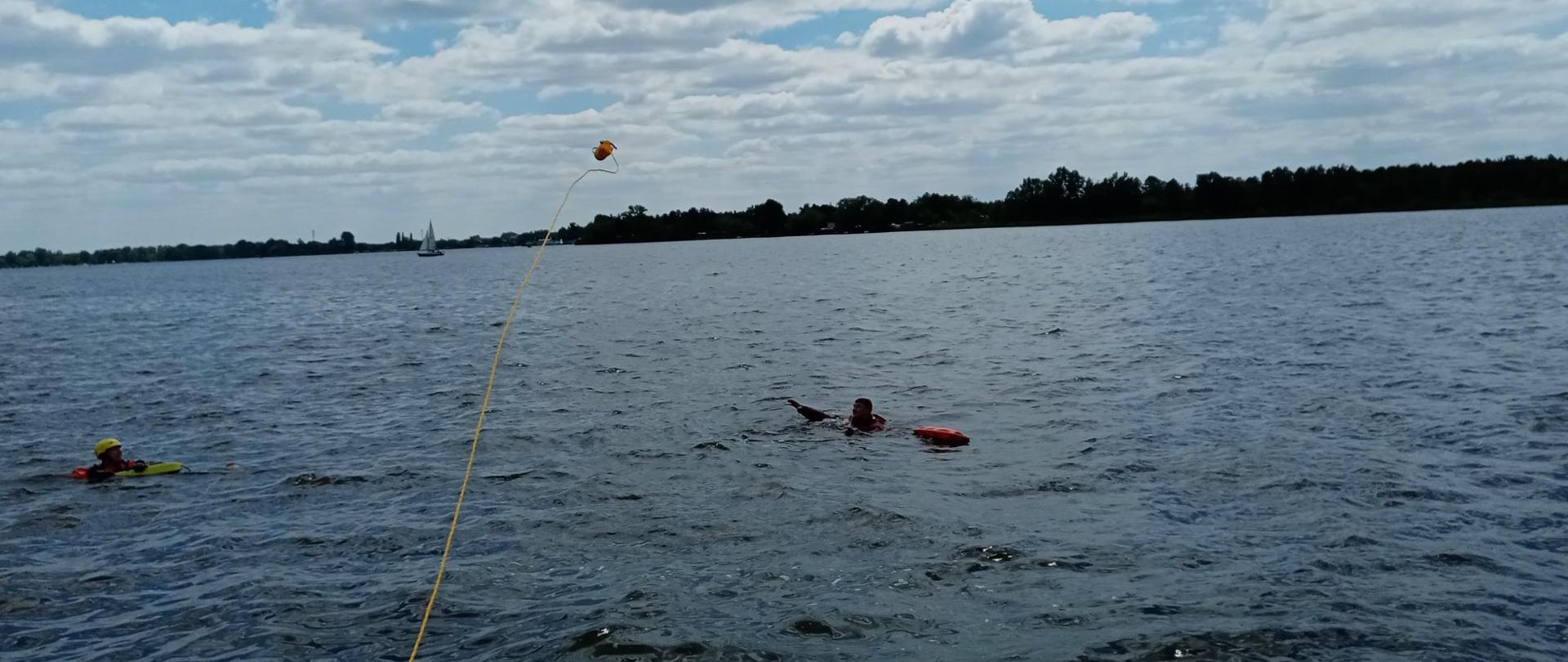 Na zdjęciu widoczna rzutka ratownicza w locie do osoby poszkodowanej znajdującej się w wodzie