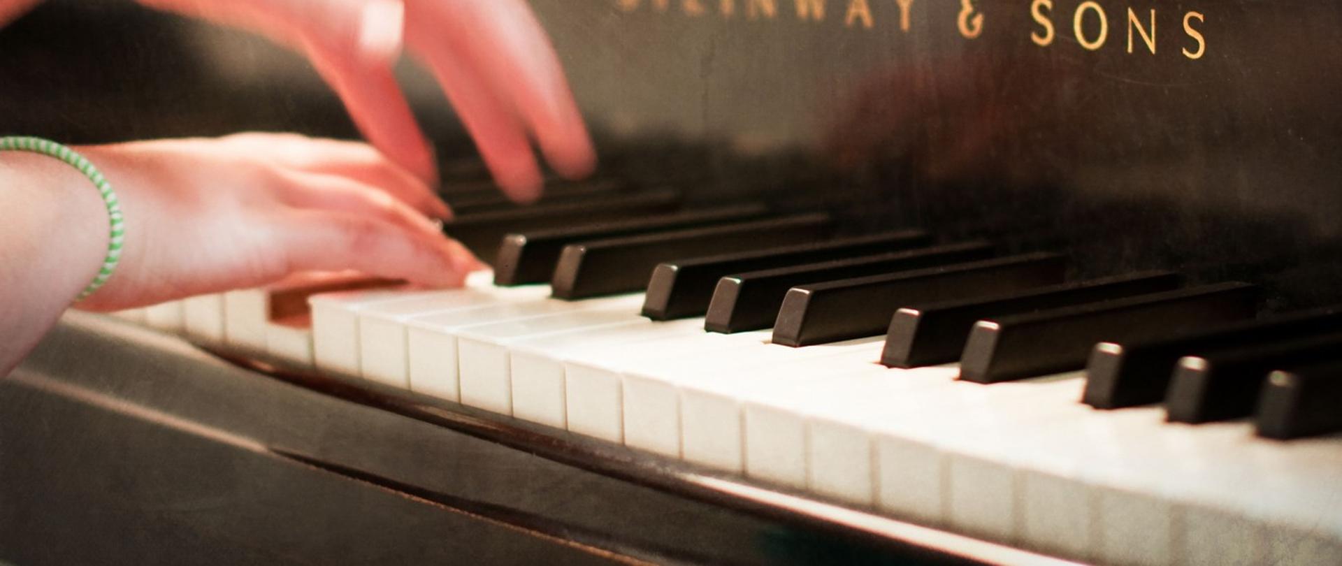 Zdjęcie przedstawiające dłonie dziecka, które grają na fortepianie