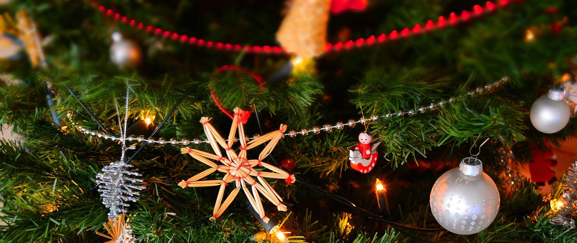 Zdjęcie przedstawia ozdoby świąteczne, bąbki oraz lampki umieszczone na choince.