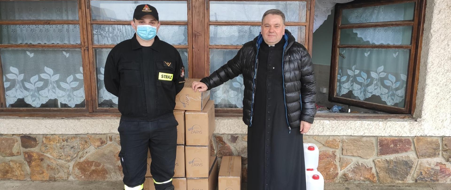 Na zdjęciu strażak PSP w umundurowaniu koszarowym w towarzystwie ks. proboszcza 