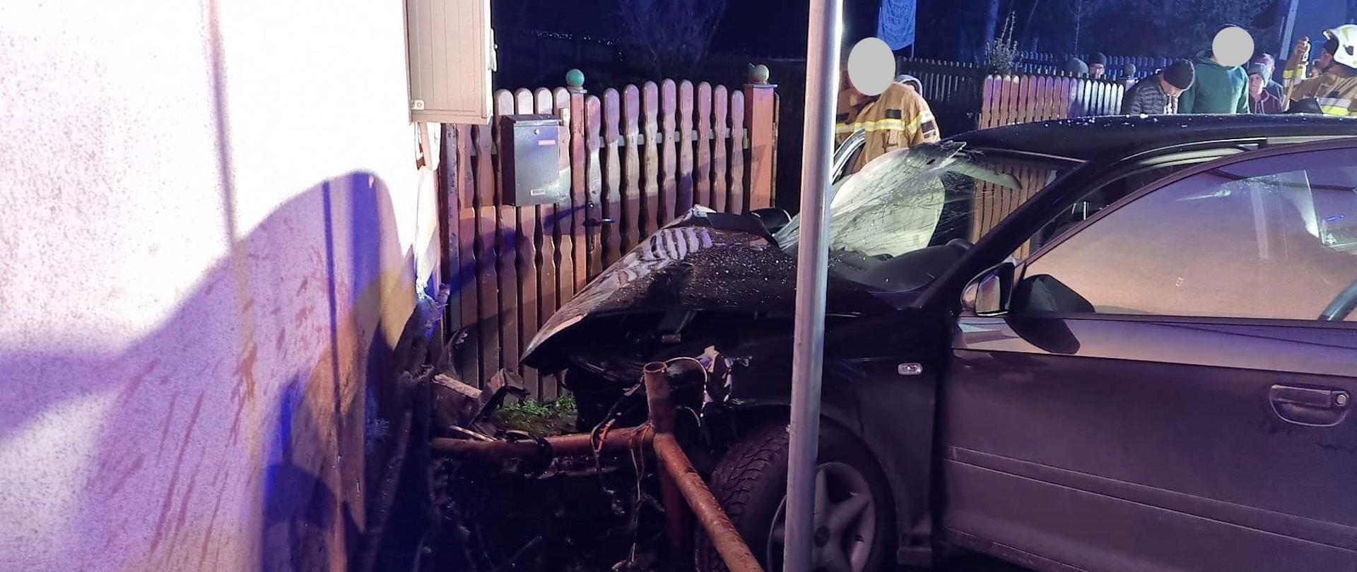 Zdjęcie przedstawia strażaków prowadzących działania ratownicze w obrębie wraku pojazdu Audi. 