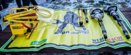 Zdjęcie przedstawia nowy zestaw hydrauliczny firmy WEBER Rescue System koloru żółtego. Zestaw leży na żółtej macie z wizerunkiem strażaka.