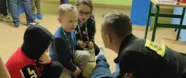 Strażak dzieciom udziela instruktażu co ćwiczeń na fantomie