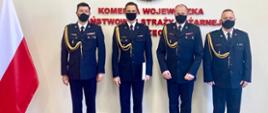 Na zdjęciu czterej Panowie Komendanci w umundurowaniu wyjściowym stoją na baczność. W tle napis na ścianie: Komenda Wojewódzka Państwowej Straży Pożarnej w Szczecinie oraz flaga Polski.