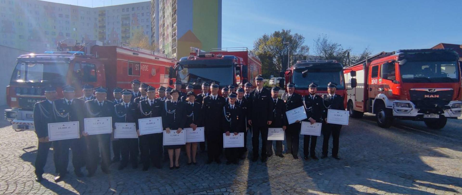 Na zdjęciu druhowie powiatu oleśnickiego wraz z Komendantem Powiatowym, w tle samochody pożarnicze. 