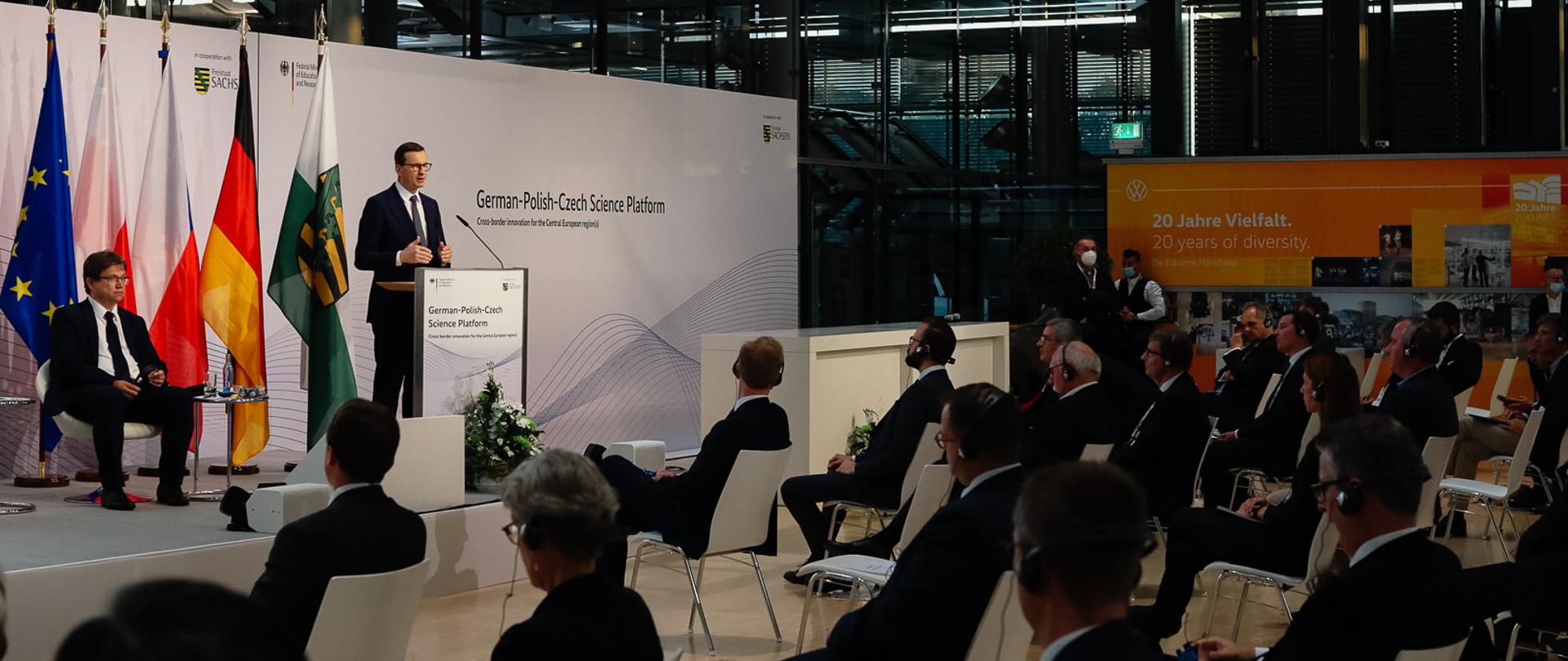 Widok na przemawiającego przy mównicy premiera.