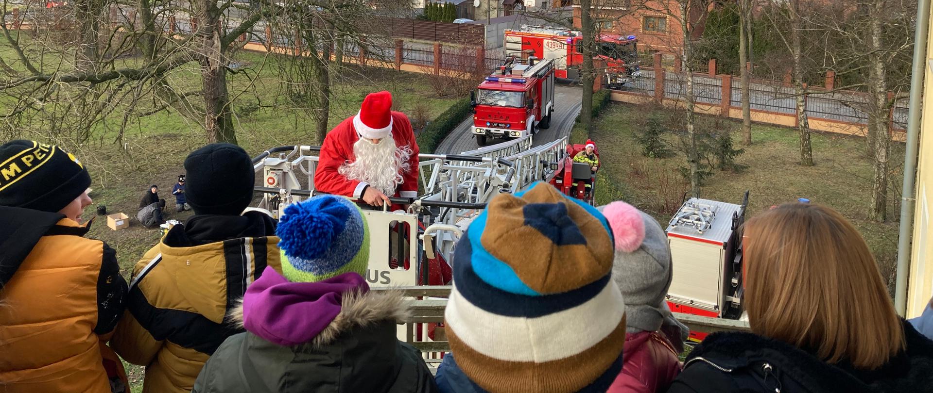 Zdjęcie przedstawia dzieciaki, które otrzymują prezenty od św. Mikołaja.