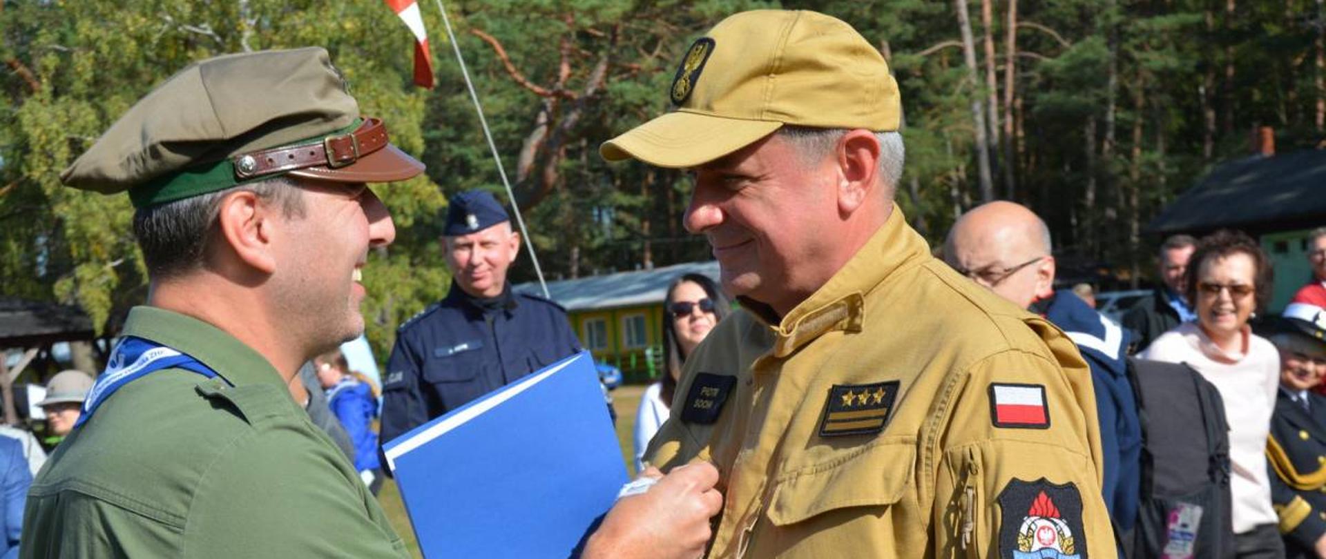 Komendant Chorągwi Gdańskiej przypina medal pomorskiemu komendantowi Państwowej Straży Pożarnej.