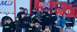 Grupowe zdjęcie dzieci wraz kadetami CS PSP na tle bojowego wozu pożarniczego