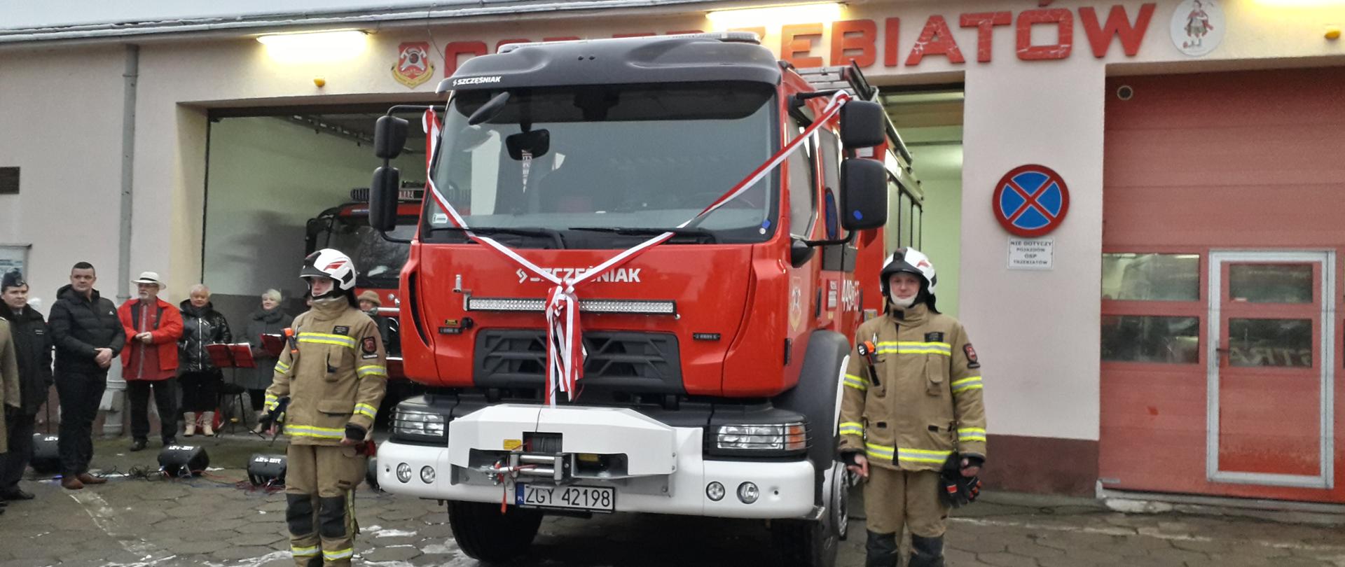 Widoczni na zdjęciu druhowie z OSP Trzebiatów przy nowym wozie bojowym Renault, w tle remiza