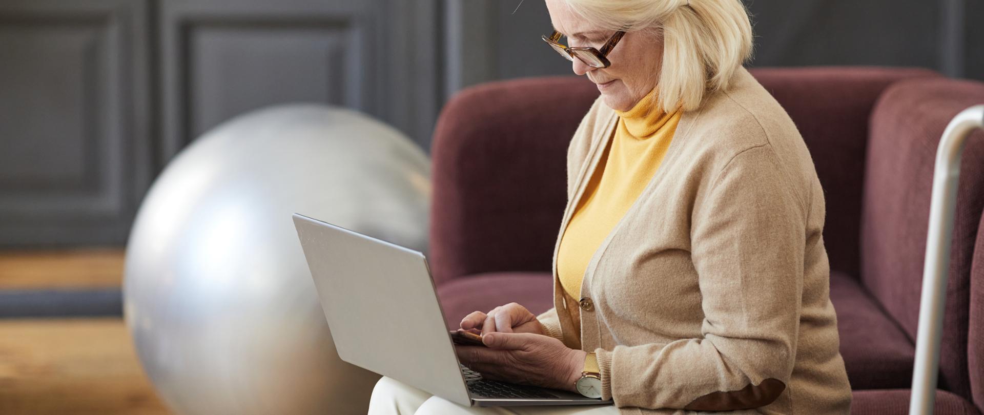 Side view portrait of elegant senior woman using laptop while relaxing in nursing home, copy space