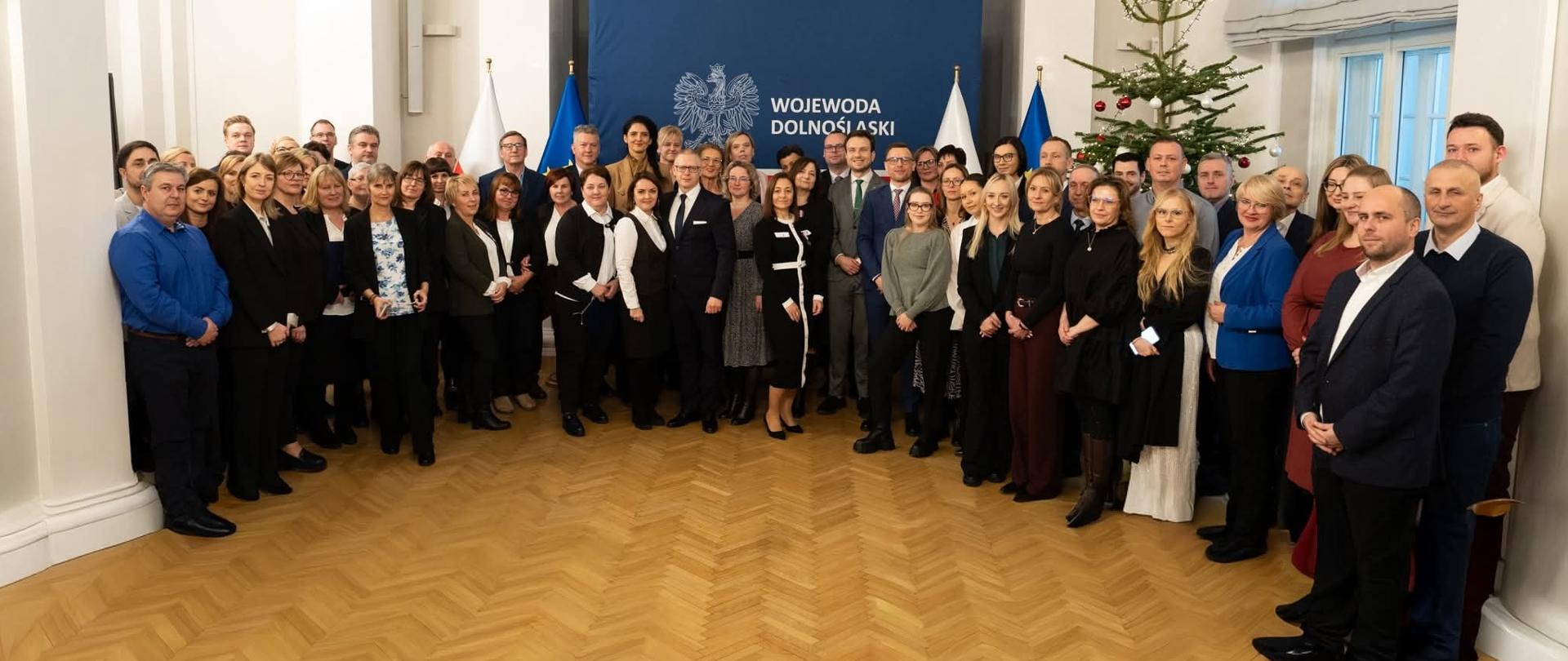 Grupowe zdjęcie pracowników Wojewódzkiego Inspektoratu Inspekcji Handlowej we Wrocławiu, Wojewody Dolnośląskiej, Wicewojewody Dolnośląskiego i gości w sali Kolumnowej Dolnośląskiego Urzędu Wojewódzkiego