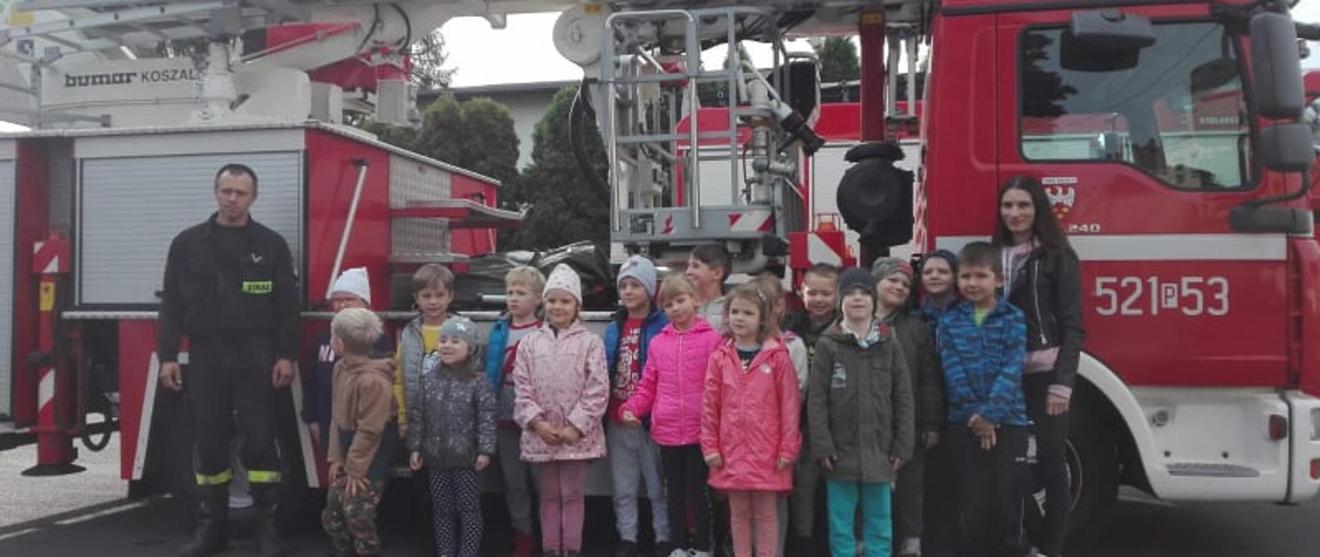Zdjęcie przedstawia grupę dzieci "Promyczki" z Przedszkola nr 2 w Obornikach na tle drabiny strażackiej.