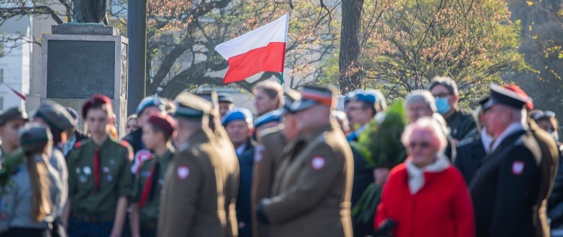 Narodowa flaga powiewa nad uczestnikami uroczystości 