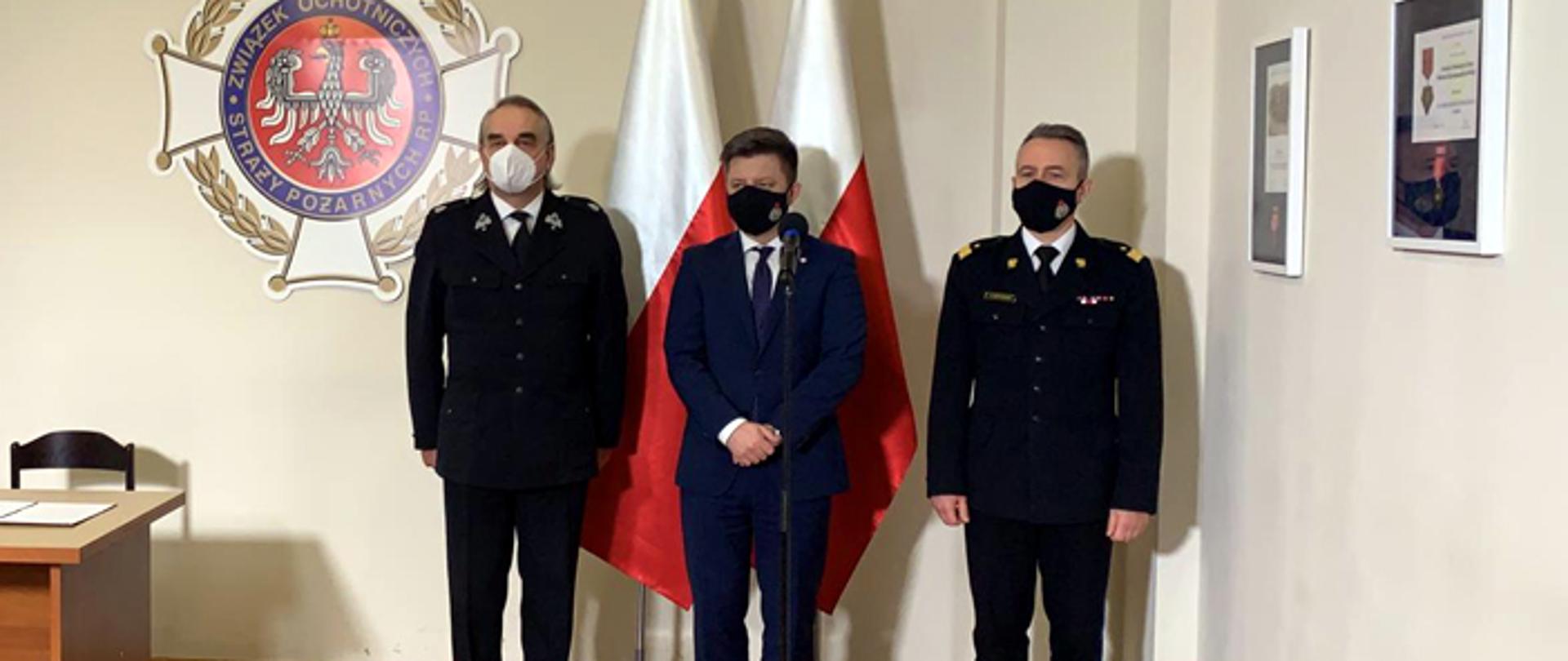 Zdjęcie przedstawia Michała Dworczyka, szefa Kancelarii Prezesa Rady Ministrów, nadbryg. Andrzeja Bartkowiaka, komendanta głównego PSP i dh. Waldemara Pawlaka prezesa ZG ZOSP RP.