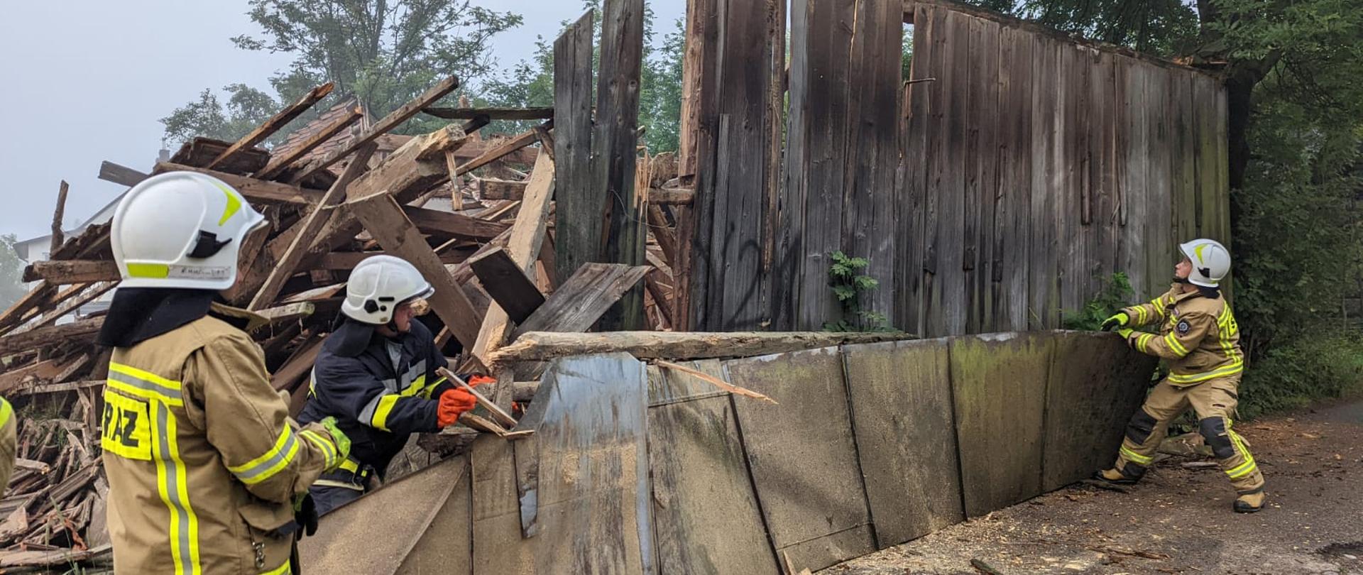 Strażacy zabezpieczają konstrukcję drewnianego budynku.