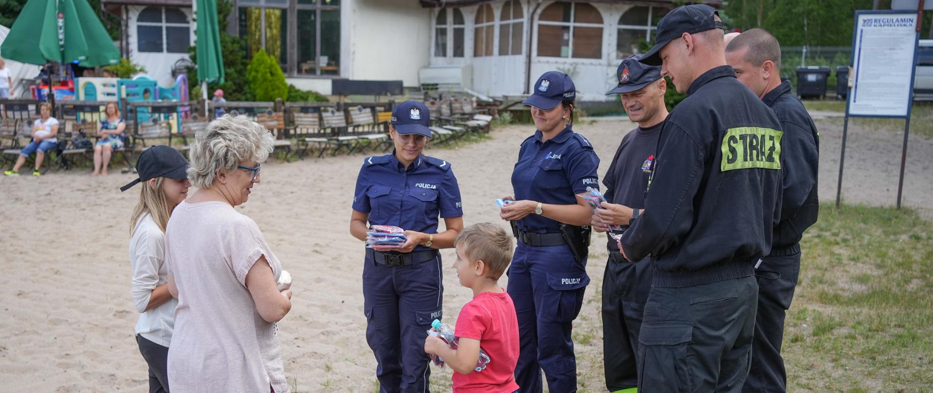 Na zdjęciu widać strażaków oraz policjantów podczas wspólnej akcji prewencyjnej na plaży jeziora Piaszczystego.