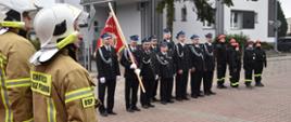 Strażacy ze sztandarem stoją w dwuszeregu