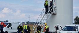 Strażacy oraz pracownicy EDP Renewables wchodzą po schodach do wnętrza turbiny wiatrowej