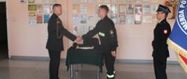 Zdjęcie przedstawia wręczenia aktu ślubowania strażakowi przez komendanta powiatowego PSP w Kole