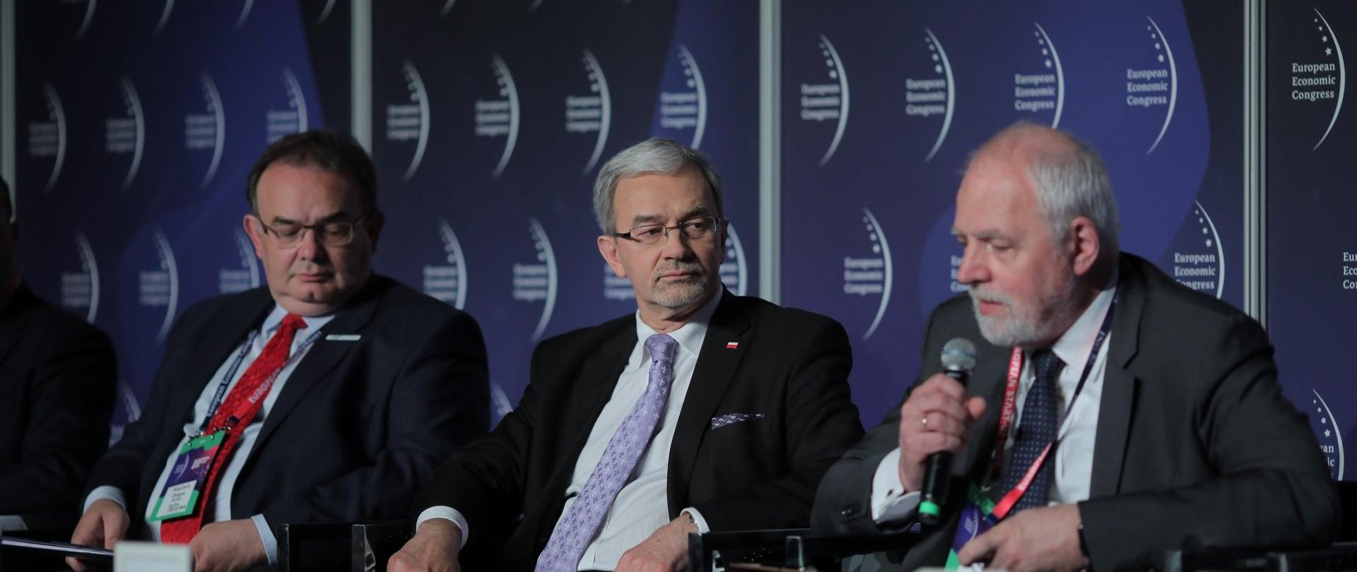 Minister Kwieciński siedzi na fotelu wśród innych uczestników debaty 