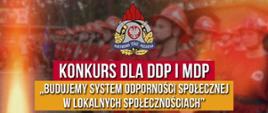 Na grafice widoczna jest grupa młodych strażaków w czerwonych mundurach i kaskach, stojących w równym szyku. Nad nimi umieszczono emblemat Państwowej Straży Pożarnej oraz tytuł konkursu skierowanego do DDP i MDP: „Budujemy system odporności społecznej w lokalnych społecznościach”. Całość ma charakter oficjalnego plakatu promującego działania edukacyjne i prospołeczne wśród młodzieżowych drużyn pożarniczych