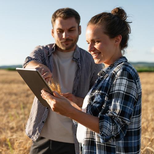 Para uśmiechniętych rolników na polu ogląda coś w tablecie